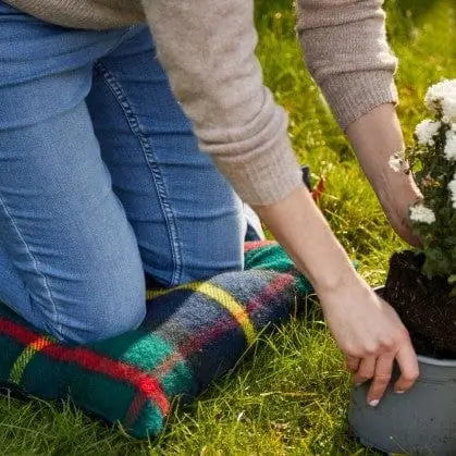 Vrouw op tartan kniekussen in de tuin